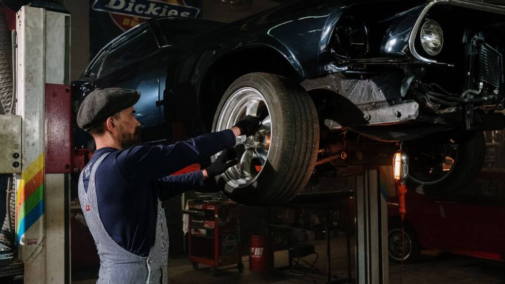 Obrazek przedsatwia mechanika samochodowego pracującego w warsztacie