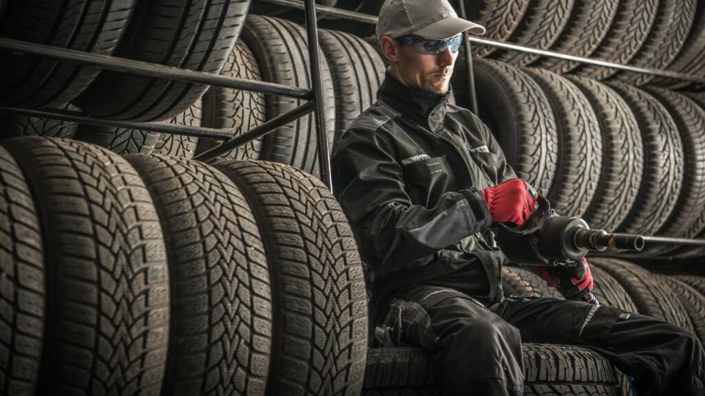 Obrazek przedsatwia mechanika siedzącego przy oponach