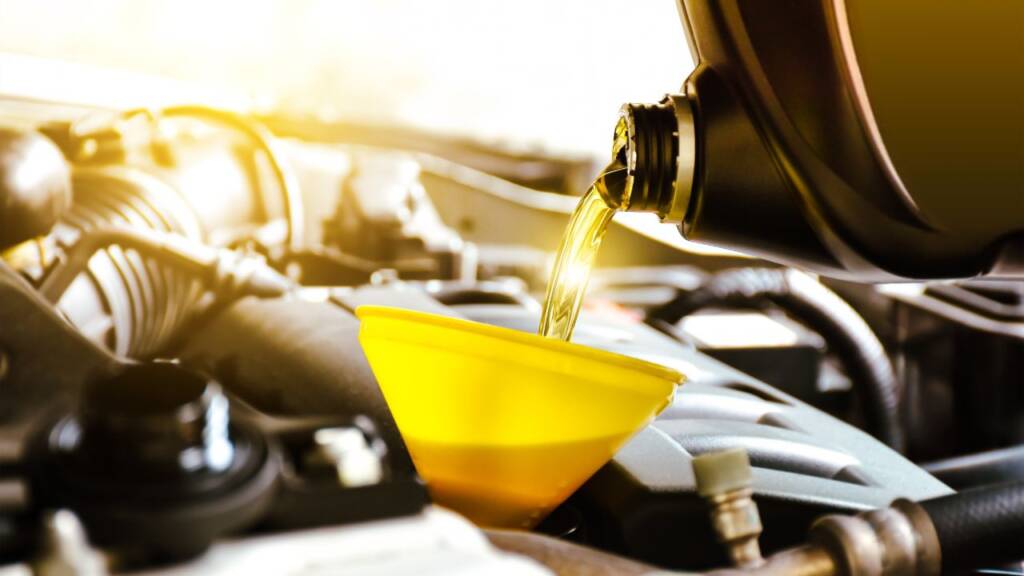 Obrazek przedsatwia nalewanie przez lejek oleju silnikowego do baku